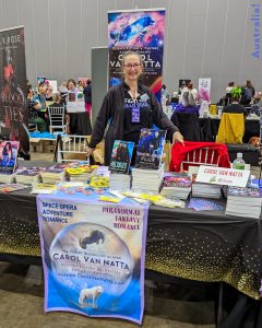 Photo of Author Carol Van Natta at a table with all her books. Taken at RARE23 Melbourne in Australia. It was a grand adventure!