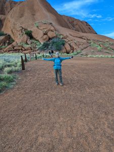 Woman standing at the base of a trail leading to Uluru - Ayers Rock in Central Australia