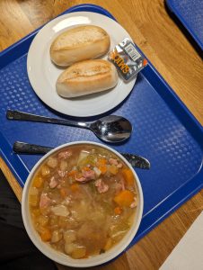 Photo of a bowl of soup and a plate of bread rolls on a serving tray. Photo (c) 2023 by Carol Van Natta.
