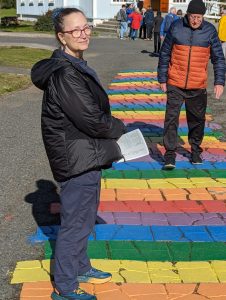 Photo of author Carol Van Natta standing on the famous Rainbow Walk in Seyðisfjörður, Iceland